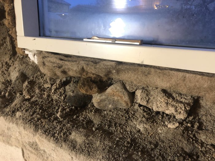 Fönsterdel i en vägg med synlig dålig betongkvalitet och isolering som ska rivas i en renovering från 40-talet.