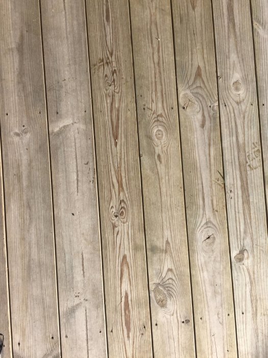 Otvättade träplankor på en altan, fortfarande smutsiga efter rengöring med grönsåpa och vatten.