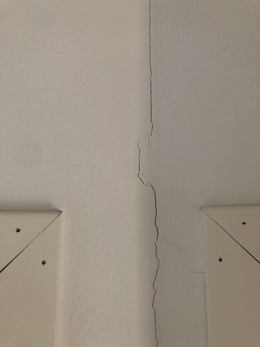 Spricka i väggen vid en dörrkarm som kan vara en sättningsskada i ett hus.
