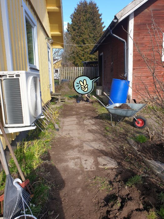 Stenplattor som avtäcks längs sidan av ett hus, grävmaskinerier och en delvis grävd gångväg.