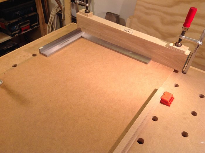 Arbetsbänk med träbit använd som anhåll fastspänd med en tving och en fotvinkel för snickeri.