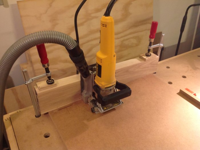 Kexfräs verktyg använder anhåll av träbit fastspänd med tvingar på arbetsbänk vid snickeri.