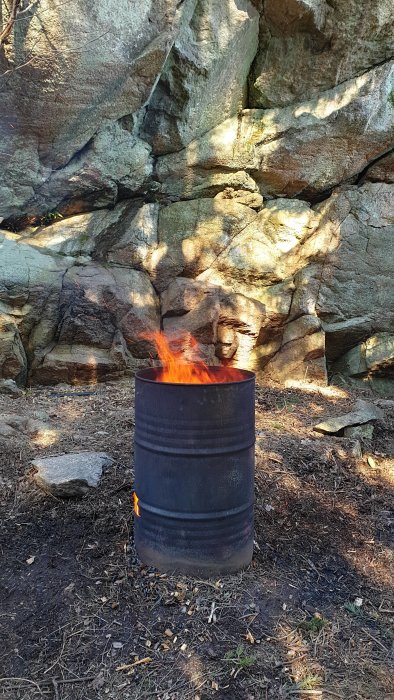 Eldtunna brinner framför en klippvägg, använd för att bränna upp material från renoveringsprojekt.