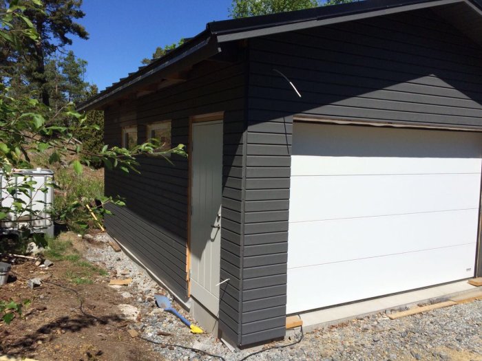 Nyinstallerad vit garageport på ett grått garage med isolering, färdigmålade väggar och belysning.