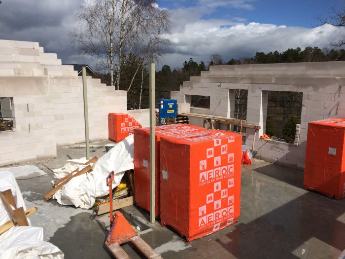 Byggplats med påbörjat taksarg och platsgjuten fönsterbalk, limträpelare vid hörnfönster och byggmaterial.