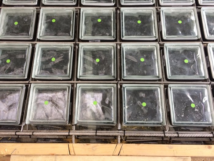 Isolerade glasblock placerade i form med synlig armering och grön markering, förberedda för gjutning.