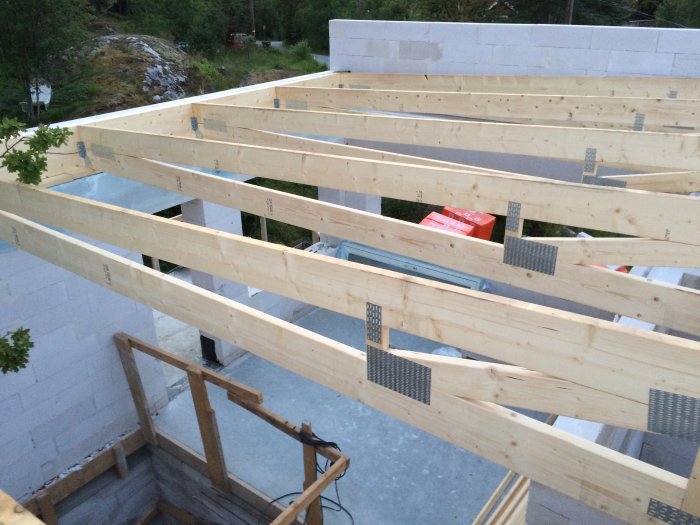 Takstolar monterade på en vitmurad byggnad med en nyligen murerad balk över ett glasblocksfönster.