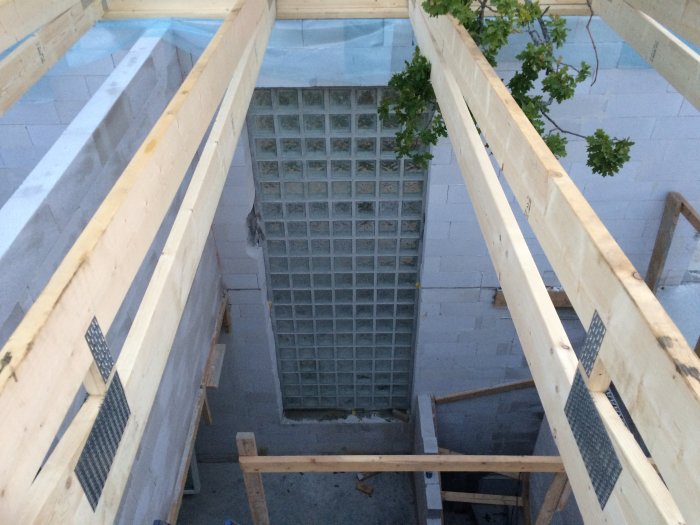 Takstolar och murad balk över glasblocksfönster i byggprojekt, vy ovanifrån.