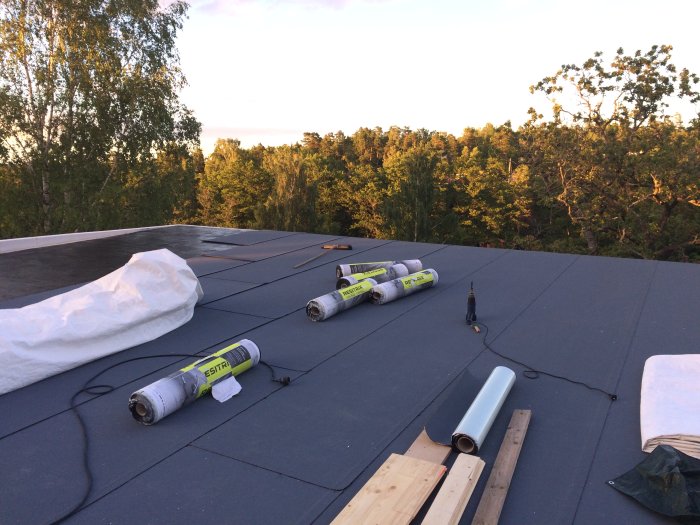 Installation av Resitrix takduk på råspont med utrullade rullar och verktyg på taket.