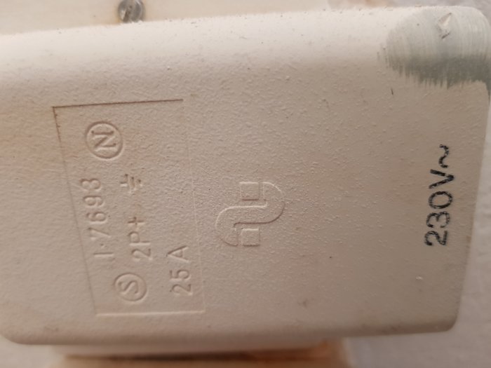 Närbild av ett vägguttag med etiketten "230V 25A" och symboler för elektrisk anslutning.