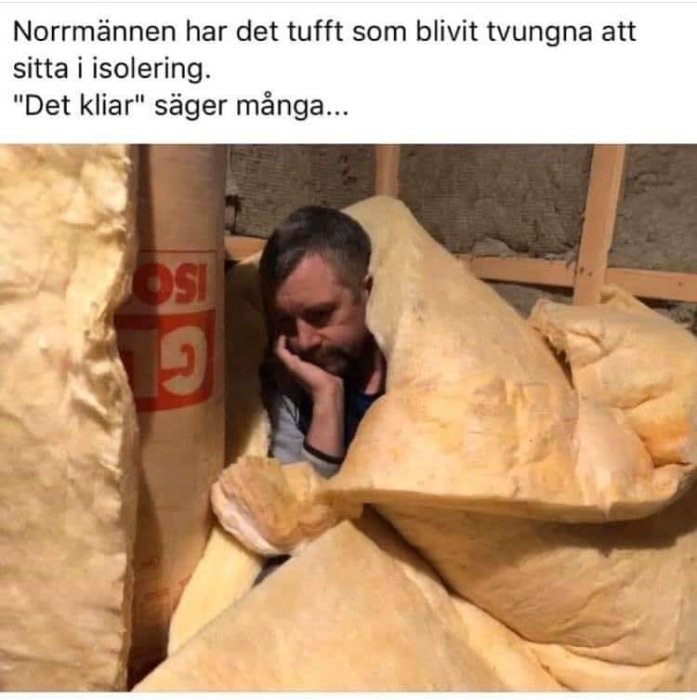 Man sitter omgiven av gul byggisolering och ser fundersam ut, med en text om att "sitta i isolering".