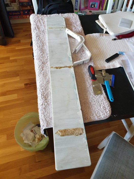 Marmorfönsterbräda med rester av jutevävsbitar och byggmaterial på golvet.