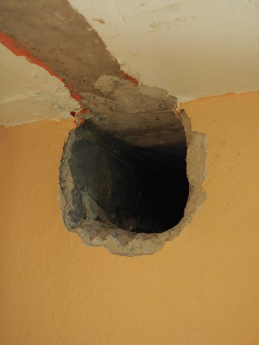 Ett gammalt hål i en källarvägg för kanaldragning, omgiven av lättbetong och rester av tätning.