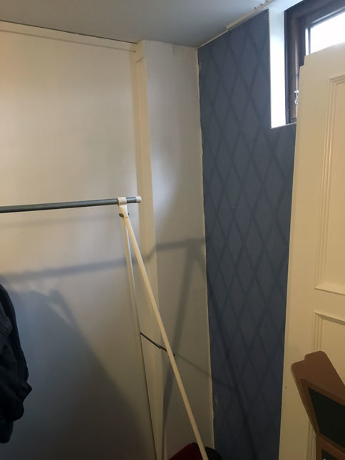 Bild av ett källarrum med vit vägg och en öppen dörr, visar även en del av en garderob.