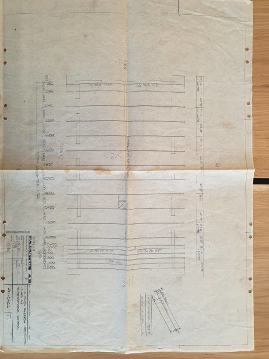 Arkitektritning av en byggnadsstruktur med måttangivelser på ett vikt, nött papper.