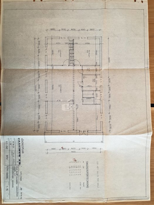 Arkitektonisk ritning av en byggnadsplan på ett papper med måttsättning och layoutdetaljer.