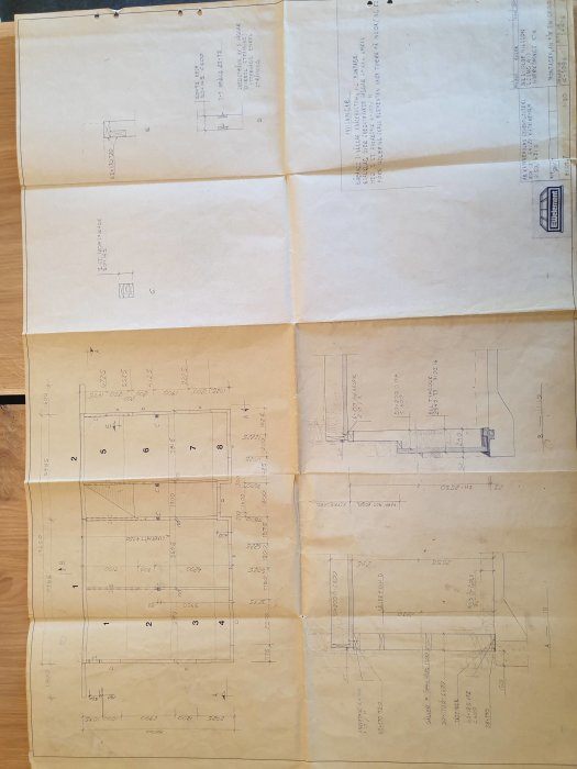 Detaljerade arkitektritningar utlagda på ett bord, synliga mätningar och dimensioner.