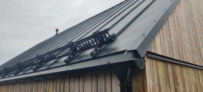 Hus utan takfot med fotplåt som leder vatten till hängränna, estetisk design över praktikalitet.