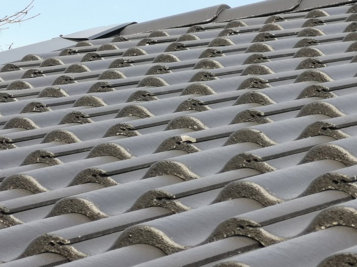 Nytt tak med betongpannor där flera pannor har skador och glipor.