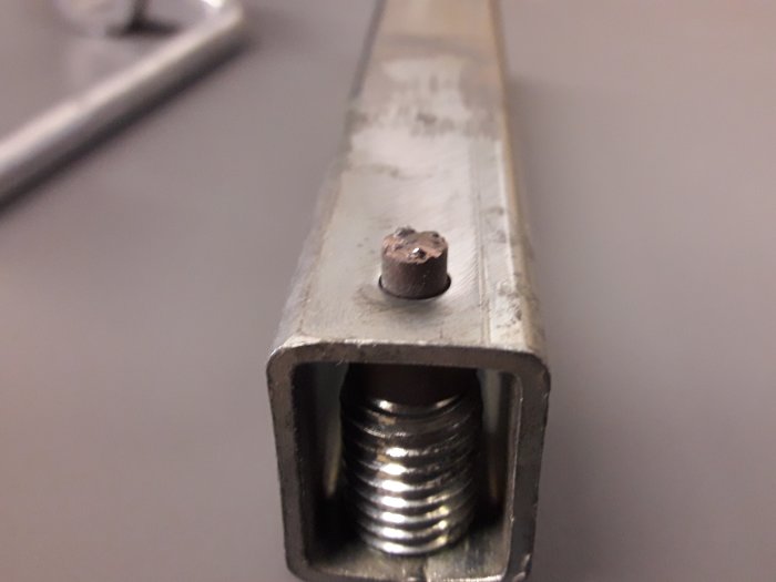 Närbild på äldre Tormek stensvarvs metallkomponent, visar justerskruv och fästpunkt.