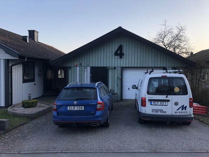 Ett hus med nummer fyra på fasaden, personbil och arbetsbil parkerade framför.