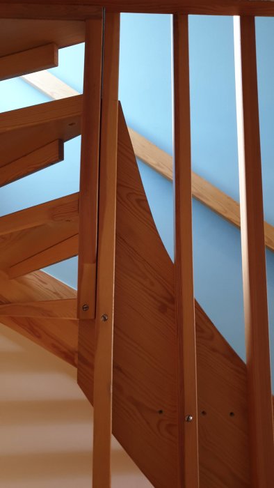 Trappa i trä med spaljé och synliga vangstycken mot blå bakgrund.