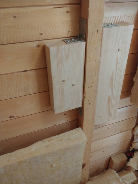 Treramme med vinkelbeslag og trestender i trevegg, omgitt av isolasjon.