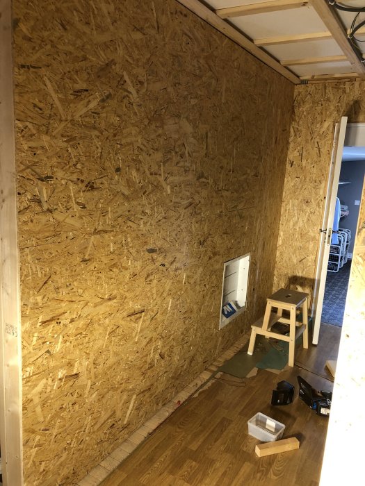 OSB-monterad vägg med LK fördelarskåp, verktyg och pall, i framtida badrum under renovering.