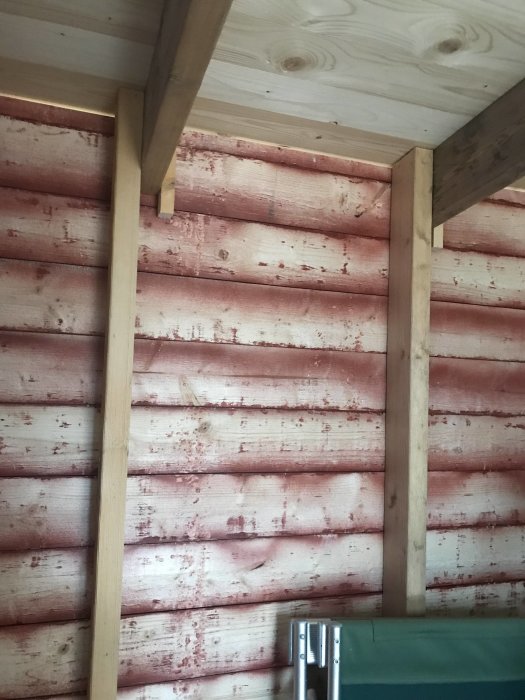Interiörbild av en hemmabyggd bod med enkla trästommar och oisolerade väggar.
