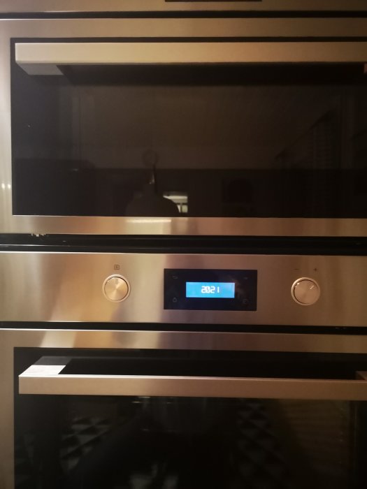 Inbyggd rostfri ugn med digital display som visar klockslaget 20:21.