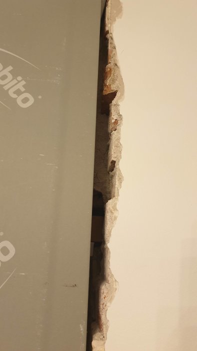 Ojämn kant där en ny gipsskiva möter en befintlig tegelvägg som lämnar ett glapp.