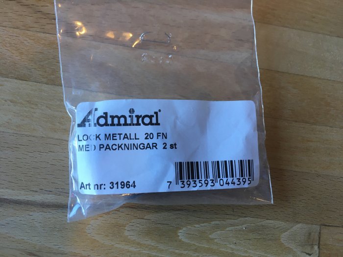 Förpackning av metalllock 20 FN med packningar på träbord.