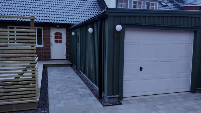 Renoverat garage med nytt tak, vit garageport och uppdaterad exteriör inklusive ny altan med spaljé och breddad uppfart.