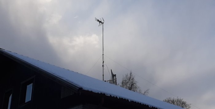 Takantenn och parabol på hustak mot molnig himmel, potentiellt problem med mottagningen.