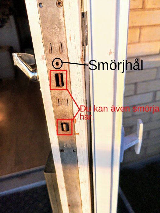 En dörr med ett markerat smörjhål och smörjbara delar på dess spanjolett.