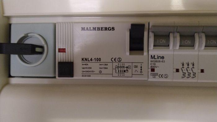 Automatsäkring i elcentral märkt 'MALMBERGS KNL4-100' med flera brytare i 'ON'-läge.