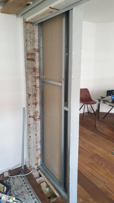 Omfattande renoveringsarbete med skjutdörrar framför en delvis rivet tegelvägg.