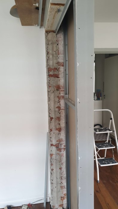 Ett pågående byggprojekt av en vägg vid en tegelstruktur med synliga skjutdörrsskenor och verktyg.