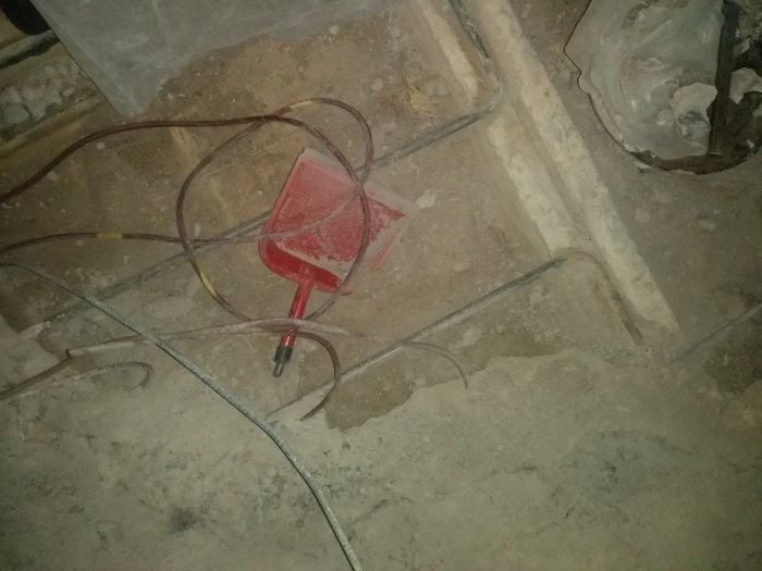 Rivning av gammalt badrumsgolv med olika lager och exponerade, potentiellt vattenburna värmeslingor från 1968.