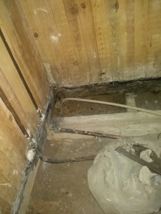 Renovering av badrum med borttaget golv som exponerar gamla rörledningar och byggnadsstruktur.