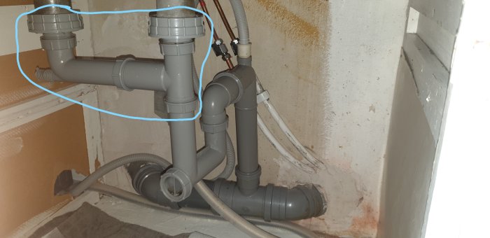 Rörinstallation under diskbänk med markerade delar för byte på grund av läckage.