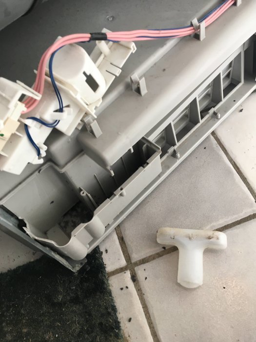 Öppen torktumlare visar inre delar och elektriska anslutningar med borttaget ludd vid sidan.