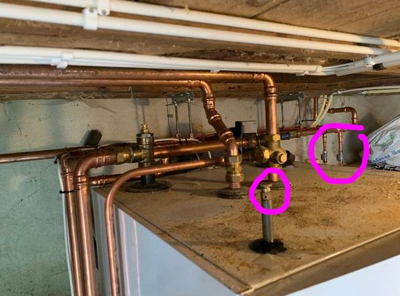Kopparledningar och komponenter för uppvärmning, inklusive inringade minikulventiler med gråa vred.