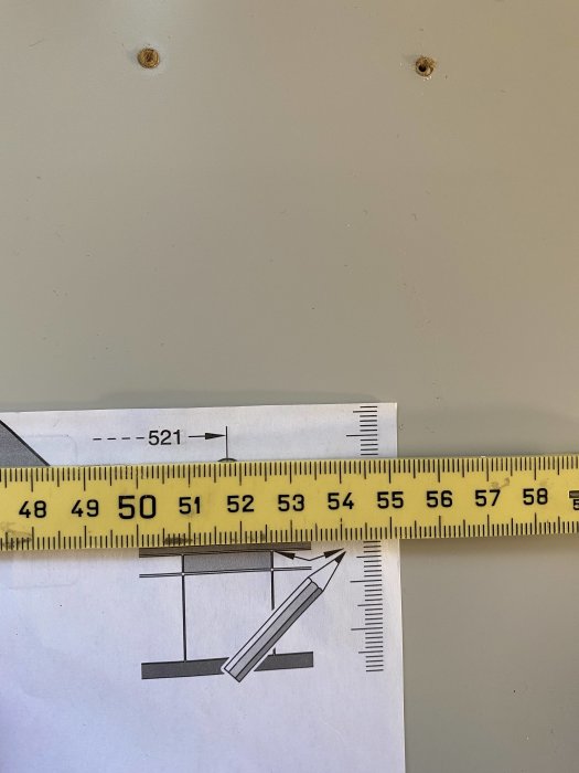 Mätband som visar 521 mm bredvid en Bosch installationsmall på en vägg.