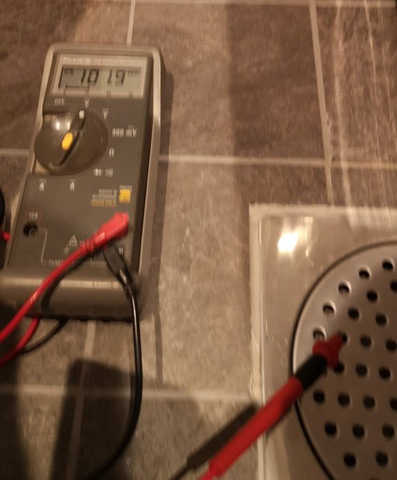 Multimeter visar 101 VAC mellan golvbrunn och vattenledning i badrum.