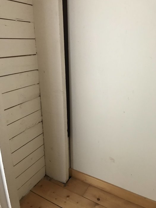 Stötta placerad i hörn av rum under snedtak i villa från 30-talet, nära vitmålade trälister.