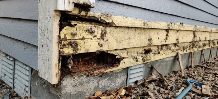 Delar av en murken yttervägg och syll på ett hus med skador efter demontering av en gammal altan.