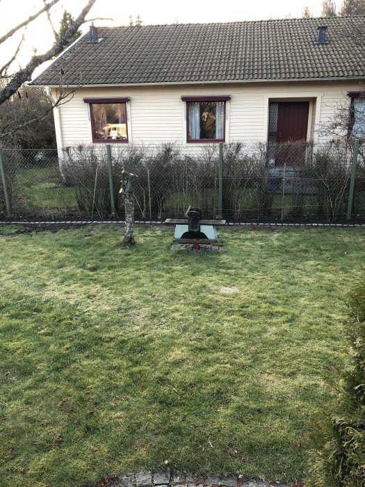 Trädgård med nyuppsatt kantsten och en brevlåda med skylt framför en enfamiljshus.