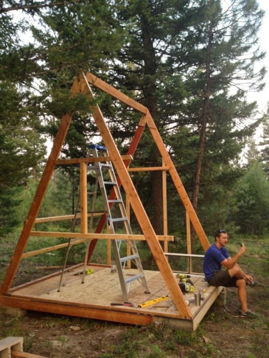 Träkonstruktion av A-stolpar för byggprojekt med person som ger tummen upp.