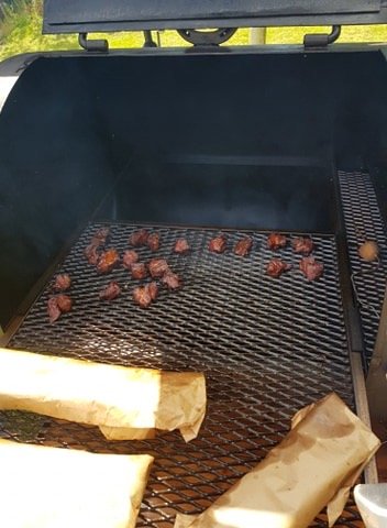 Grillad mat på en öppen grill med rökspån och pappersknyten vid sidan.